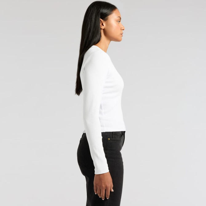 A white long-sleeve t-shirt is displayed on a model, shown from the side, paired with black jeans. It has a logo.