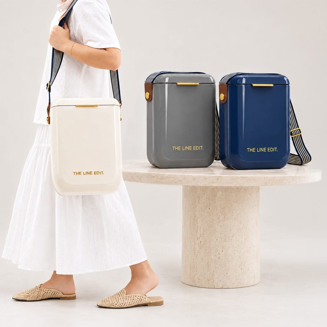 A person carries a cream cooler bag, with grey and navy cooler bags displayed beside them. All have a branding logo.