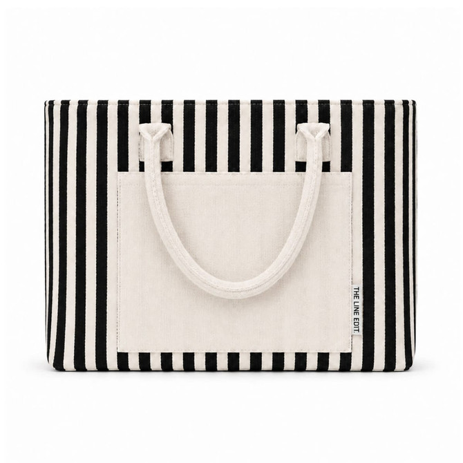 A striped tote bag in black and white with a large front pocket and two sturdy handles. Features a logo.