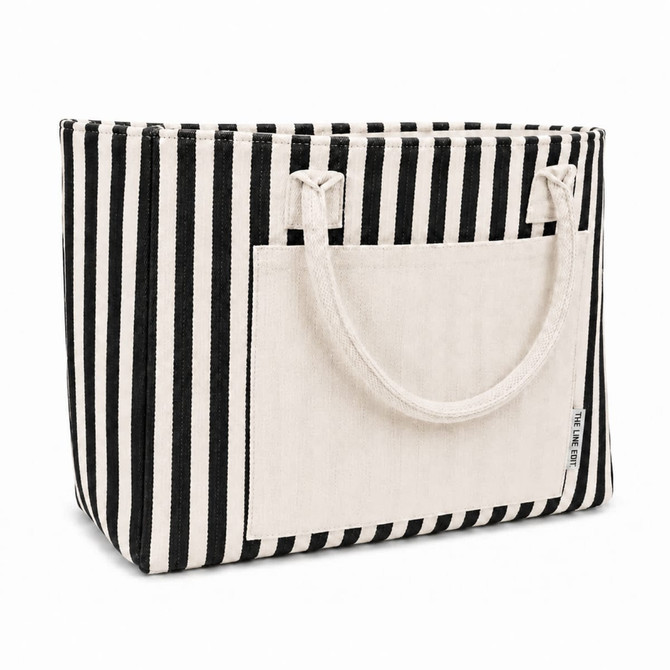 A striped black and white tote bag with a neutral-tone pocket and durable handles, featuring a branding logo.