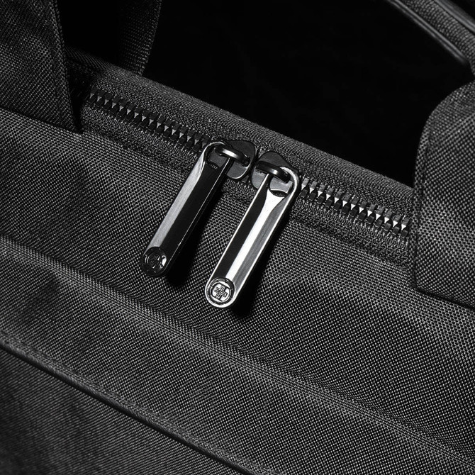 A close-up of a black laptop bag featuring dual silver zippers and a textured exterior.