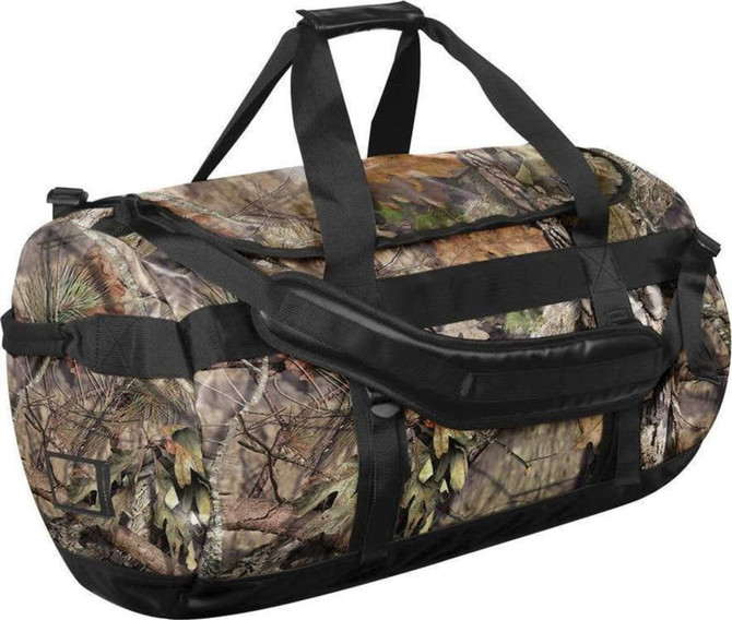 A large waterproof gear bag in a camouflage pattern with black straps and handles. Features a brand logo.