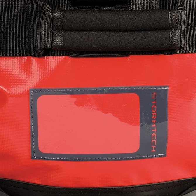 A medium waterproof gear bag in red with black accents, featuring a clear ID holder and branding.