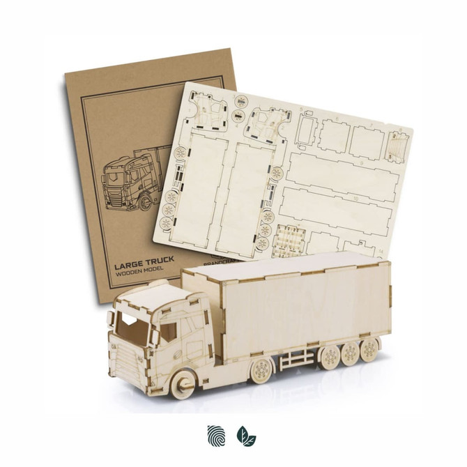 A wooden model of a large truck in natural finish, with assembly instructions displayed beside it.