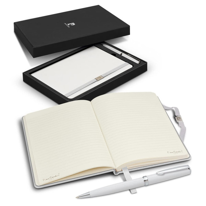 A polished white notebook with lined pages beside a silver pen, presented in a sleek black gift box with a logo.