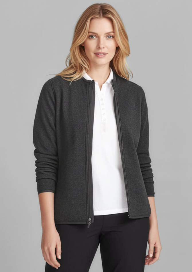 A woman wears a dark grey polar fleece jumper with a zip front, paired with a white top and black trousers.