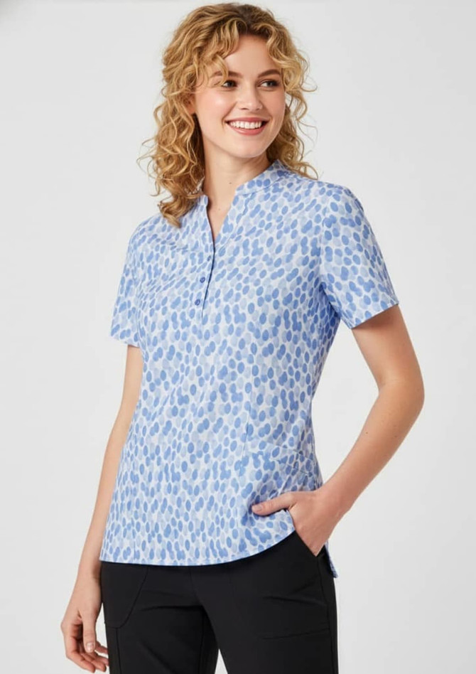 A short-sleeved women's tunic in light blue with a stardust print design and a collar, featuring a logo.