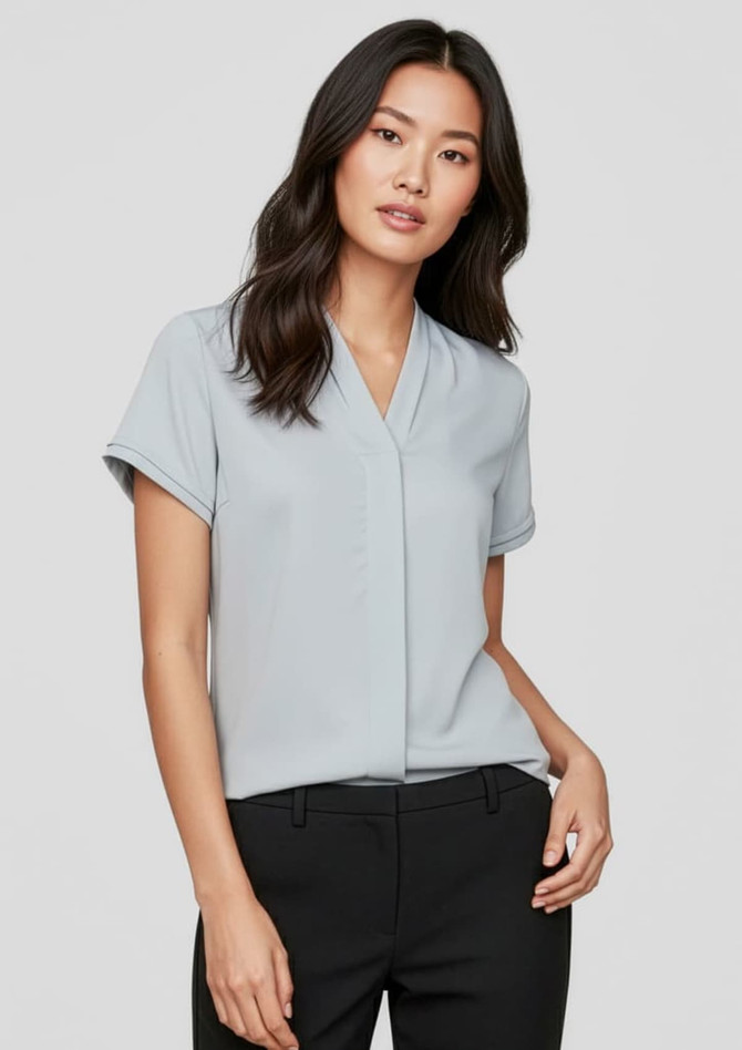 A light blue short sleeve button-up shirt with a relaxed fit, featuring a logo on the fabric.