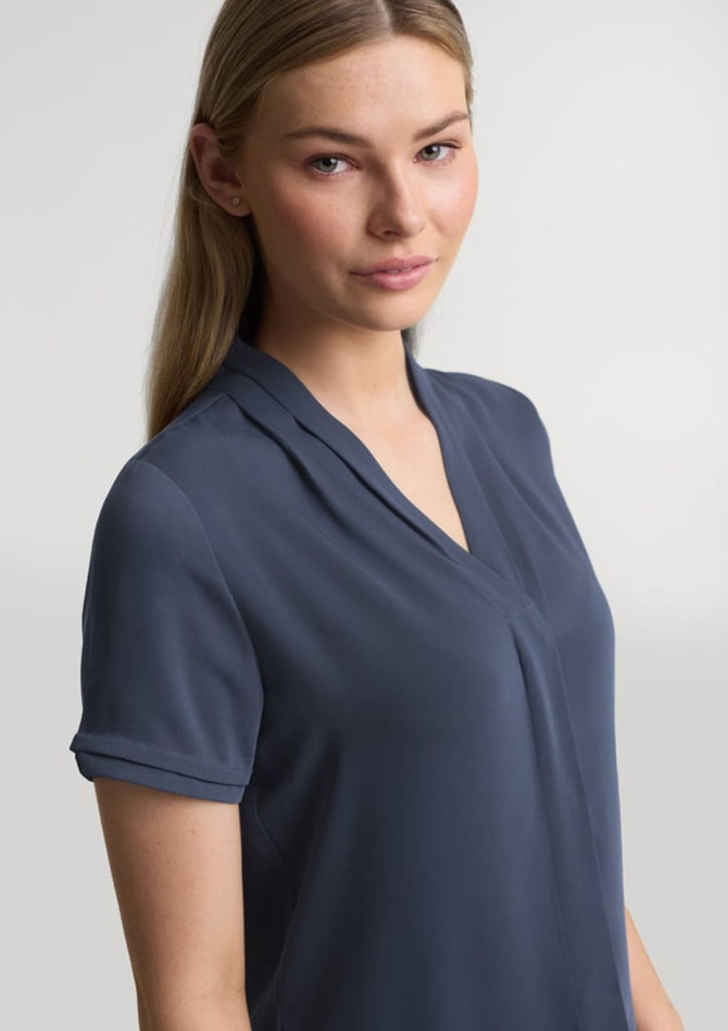 A women's short sleeve button-up shirt in navy blue with a relaxed collar and rolled sleeves. Contains a logo.