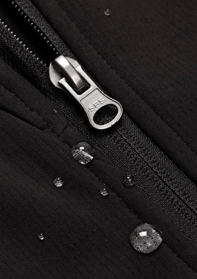 A close-up of a black soft shell jacket featuring a zip and droplets of water on the fabric.