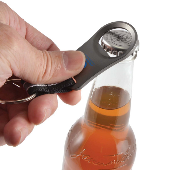 A drink bottle opener, in grey colour, with a keyring attachment, being used on a glass bottle. Includes a logo.