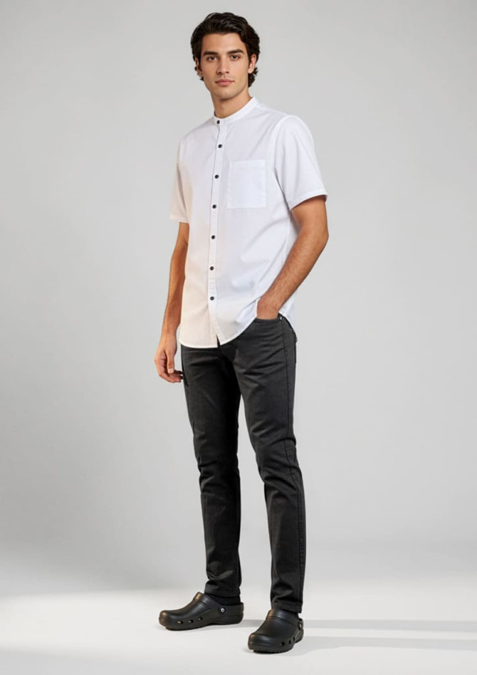 A white short sleeve chef shirt with a chest pocket, paired with black trousers and black shoes. Features branding.