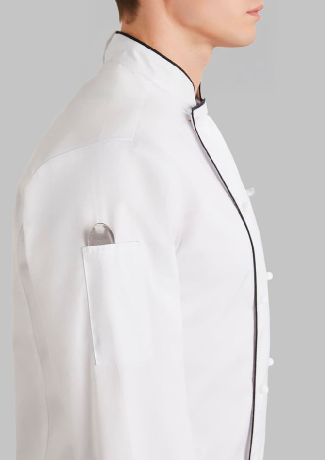 A white long sleeve chef jacket with a black trim, featuring a pocket on the sleeve, displayed on a neutral background.