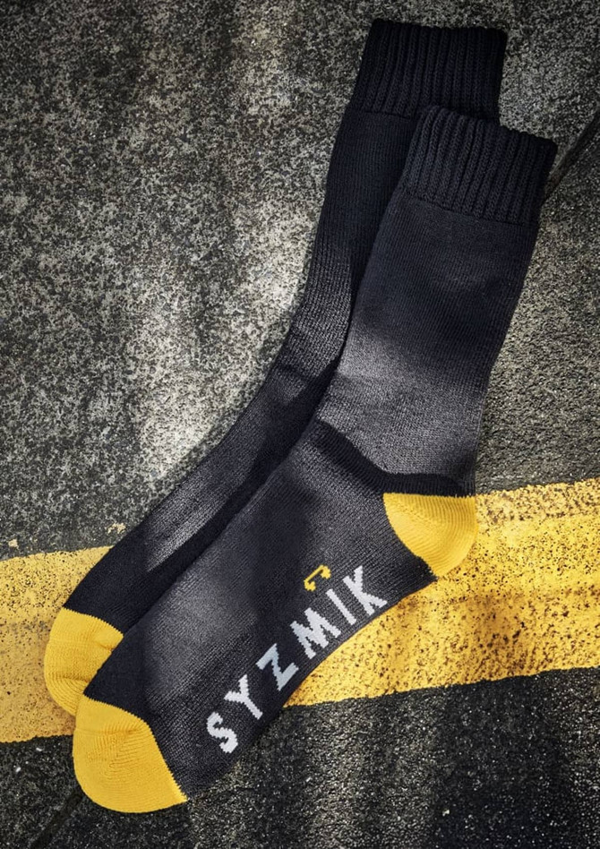 A pair of black work socks featuring yellow contrast at the toe, with branding.