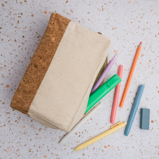 A cream utility case with a cork top, surrounded by assorted colourful pens and a pencil.