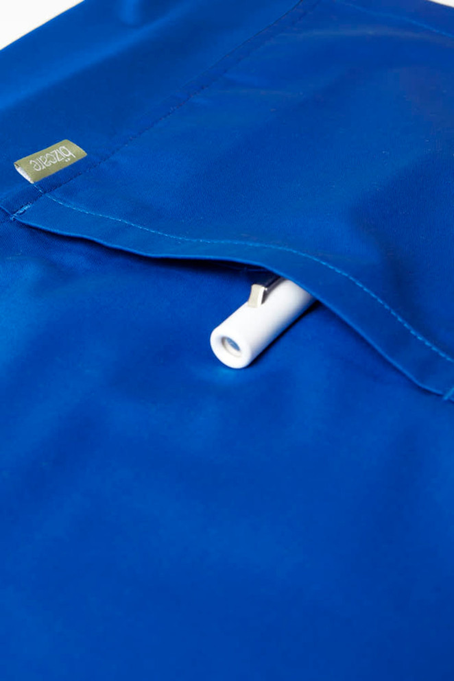 A blue men's scrub top featuring a pocket with a white insert, and a logo on the fabric.