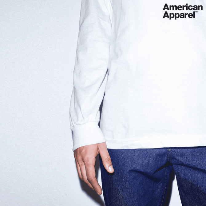 A white long sleeve fine jersey T-shirt with a logo, paired with blue denim jeans.