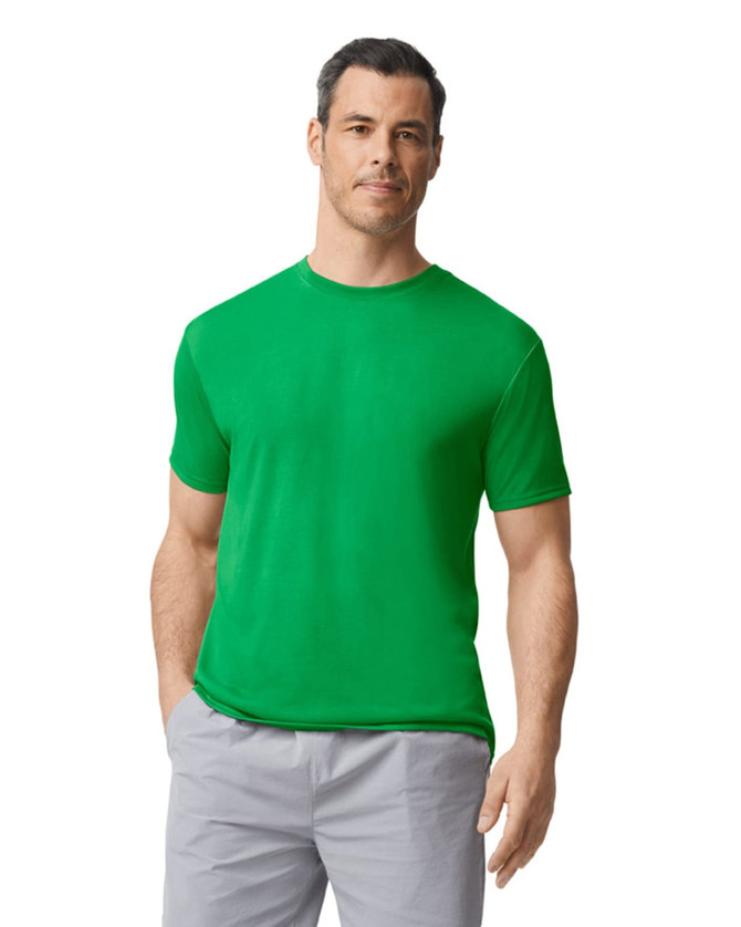 A green Gildan Performance adult T-shirt on a male model, paired with light grey trousers. The shirt has a logo.