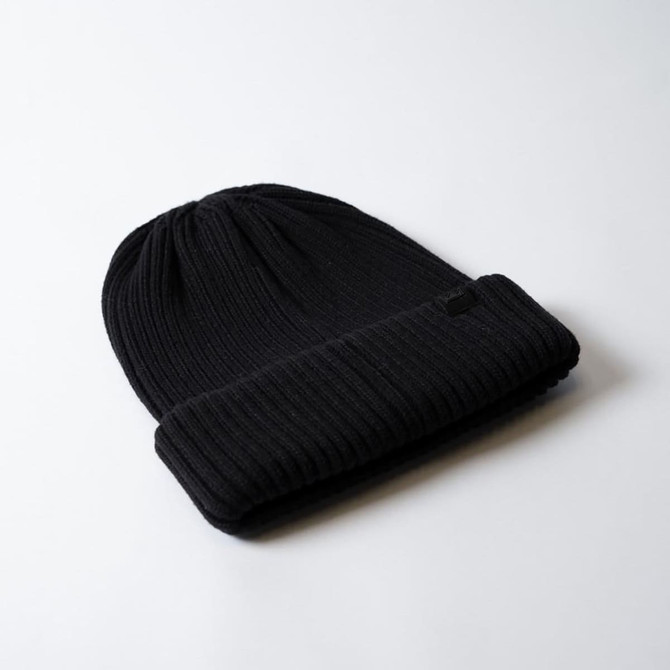 A black ribbed beanie with a folded cuff, featuring a small logo on the side.