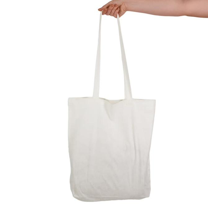A hand holding a large, white tote bag with long handles. The bag features a logo.