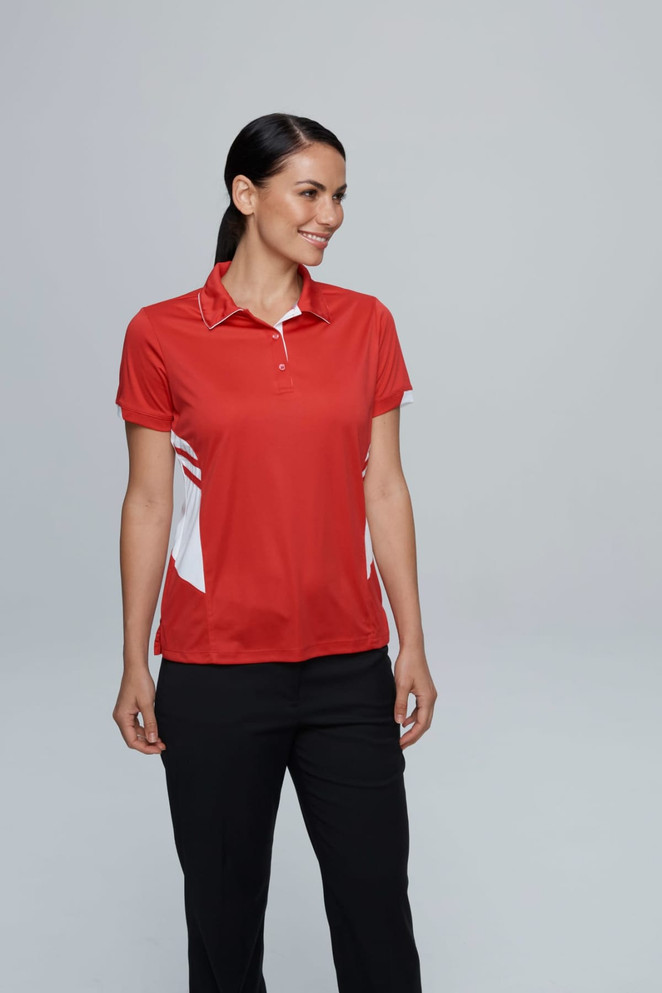 A red polo shirt with white accents and a branded logo, modelled by a woman in black pants.