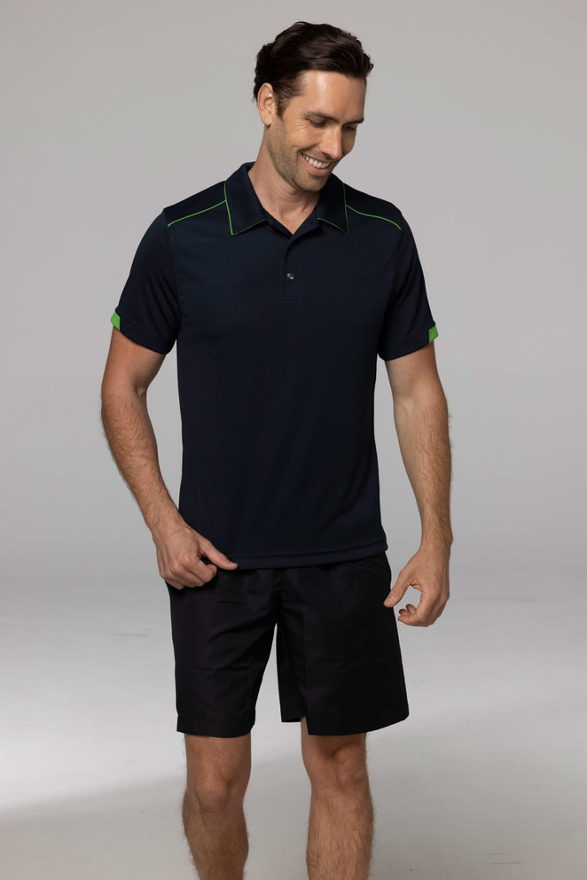 A dark navy polo shirt with green accents, modelled by a man paired with black shorts. The shirt features a logo.