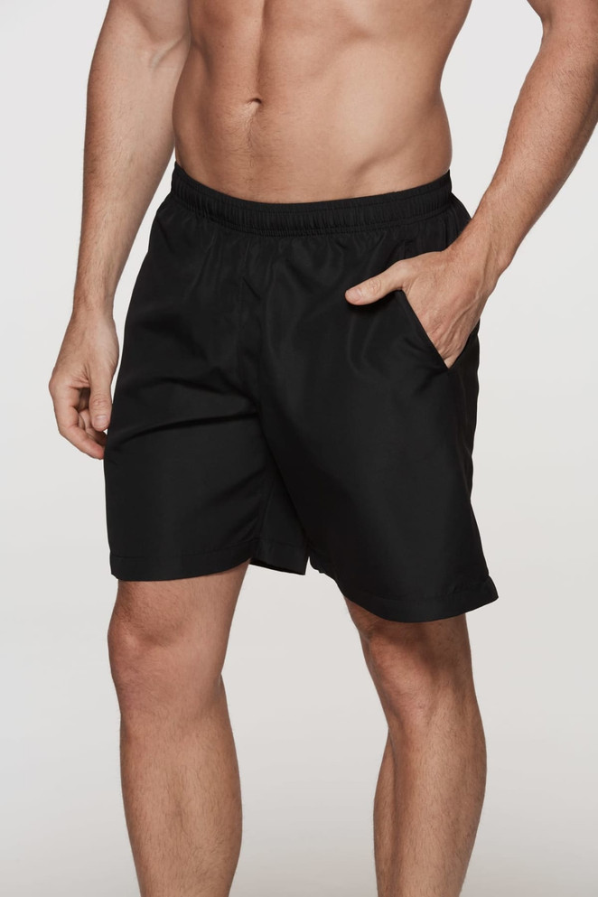 Black sports shorts with an elastic waistband and side pocket. The model is standing and showcasing the shorts.