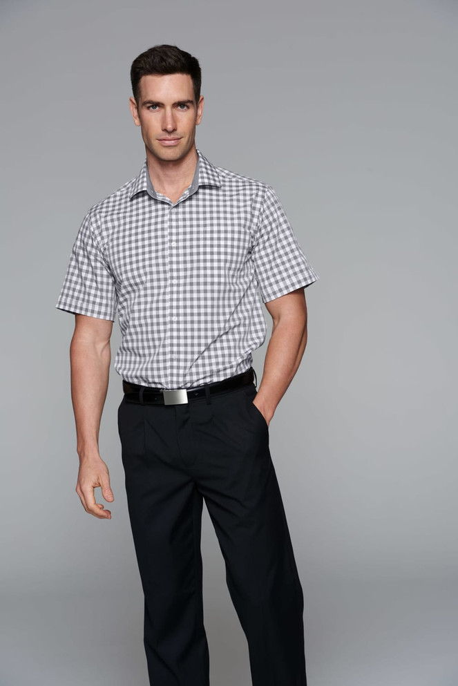 A man wearing a short sleeve, checkered button-up shirt in grey and white, paired with dark trousers.