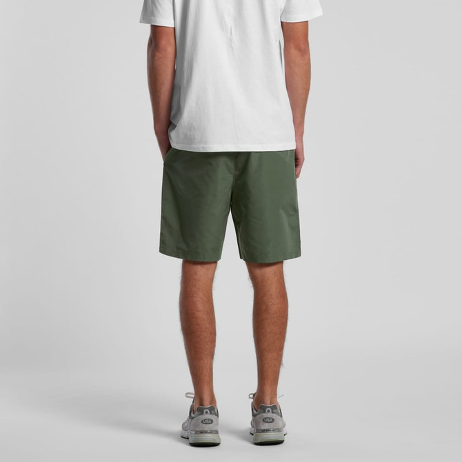 Active training shorts in green, featuring an elastic waistband and a logo, viewed from the back, paired with a white shirt.