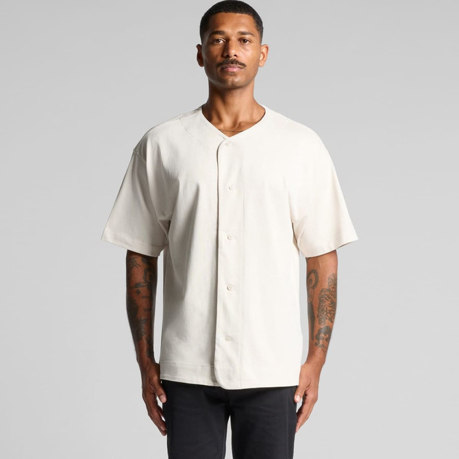 A heavy baseball jersey in cream colour, featuring a button-up front and short sleeves. The model stands in a neutral pose.