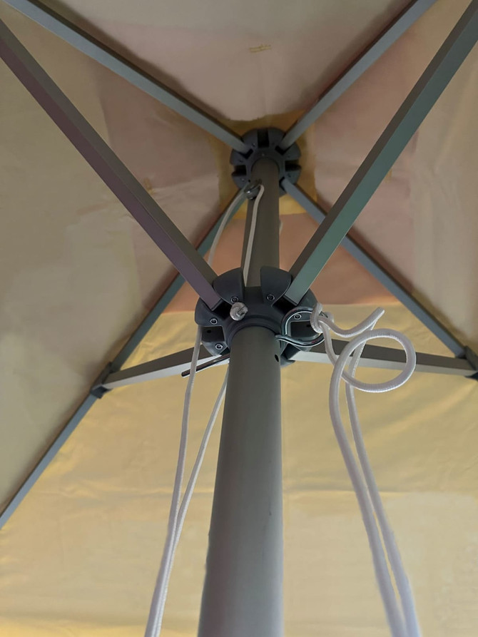 A café umbrella with a valance, featuring a beige canopy and a grey metal frame, seen from underneath.