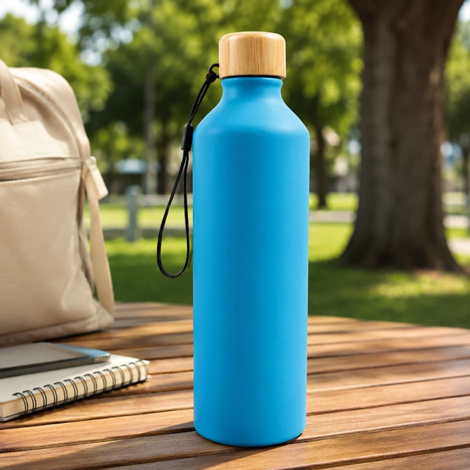 A drink bottle in bright blue with a bamboo lid, featuring a logo, set on a wooden table outdoors.
