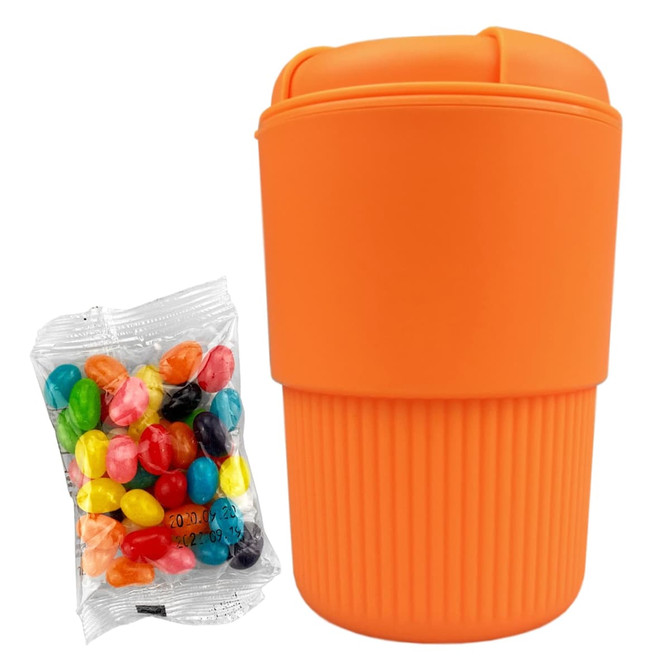 An orange reusable coffee cup with a ribbed design next to a bag of colourful jelly beans.