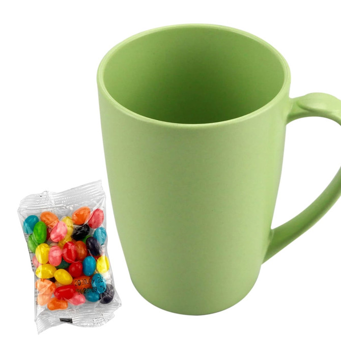 A green bamboo mug beside a packet of colourful jelly beans. The mug has a handle and a smooth finish.