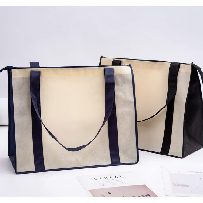 Two large zipped shopping bags in cream and black, featuring sturdy handles and a logo on one side.