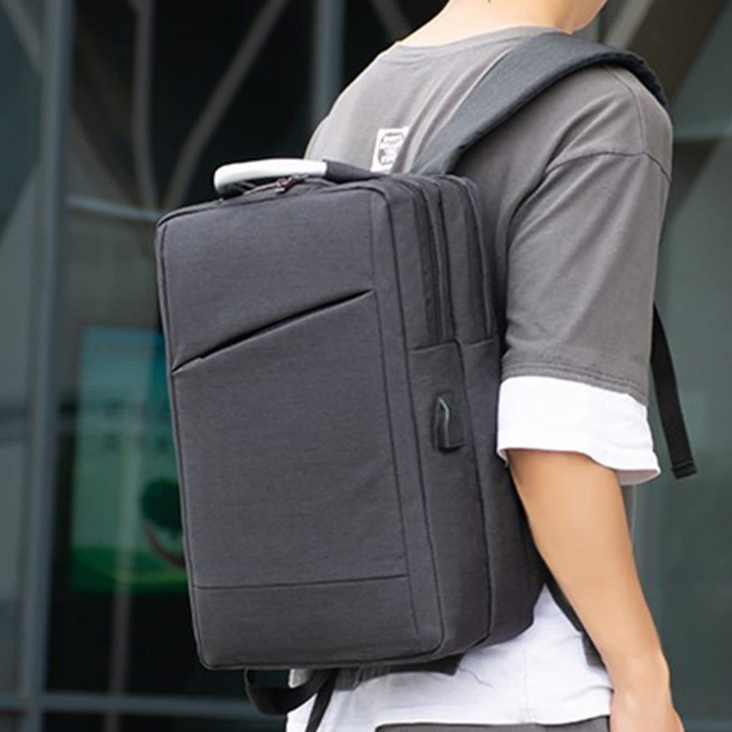 A black laptop backpack is worn on the back of a person, featuring a sleek design and a handle on top.