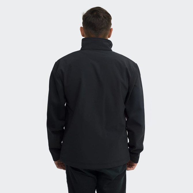 A black soft shell jacket with a high collar, viewed from the back, featuring a logo on the sleeve.