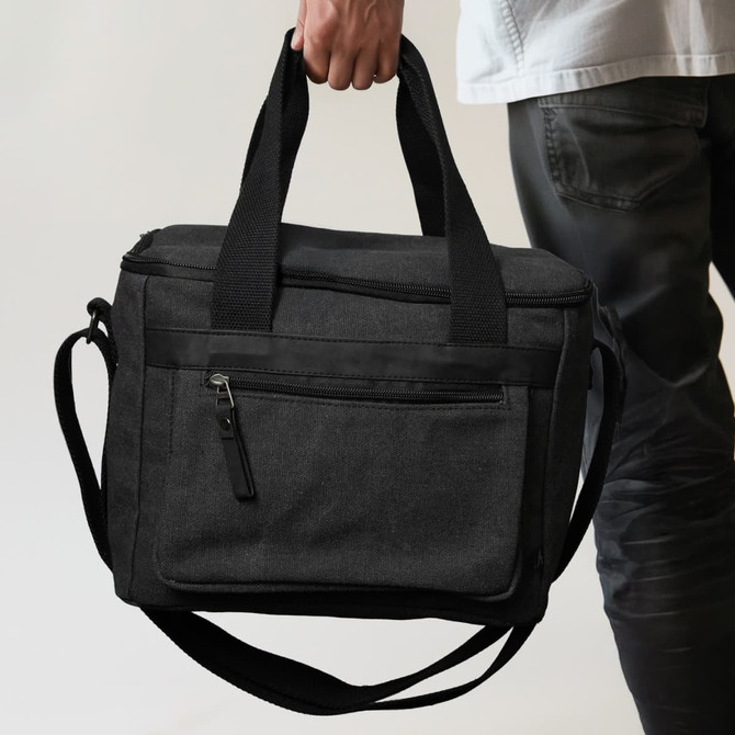 A black canvas cooler bag with two handles and a shoulder strap, featuring a front zip pocket.