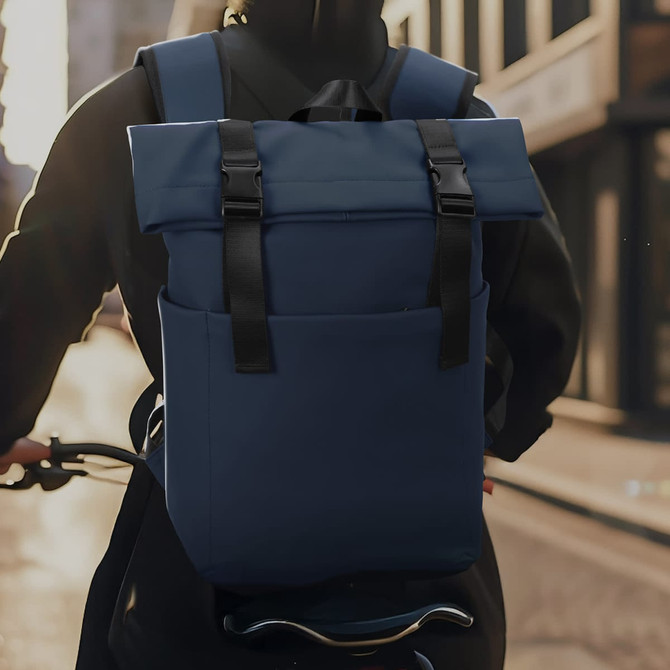 A navy blue soft-touch flap backpack with adjustable straps, featured on a person riding a bike in an urban setting.