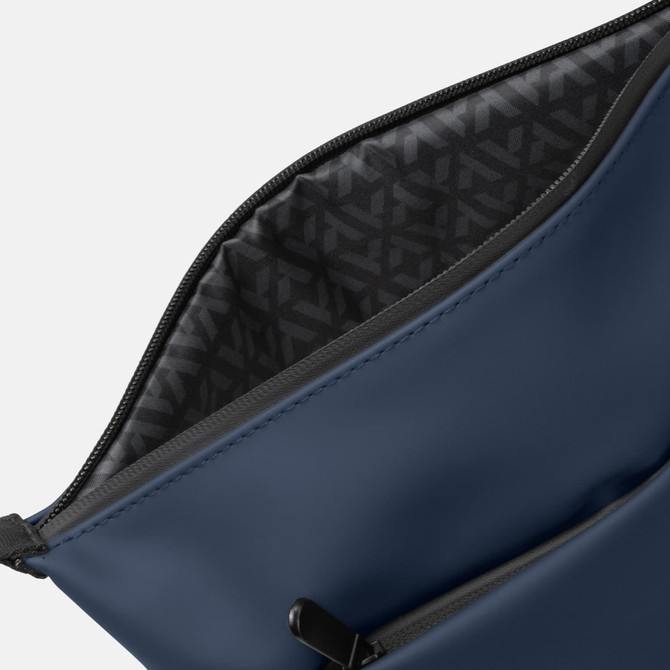 A soft-touch navy toiletry bag with a patterned interior and a zip closure. Features a logo on the exterior.