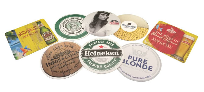 A collection of circular cardboard drink coasters in various designs and colours, featuring different beer brands and logos.