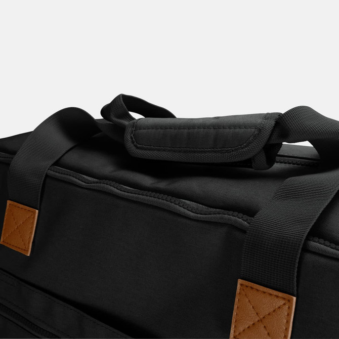 A black duffle bag with tan leather accents and padded handles. It features a sturdy design for durability.