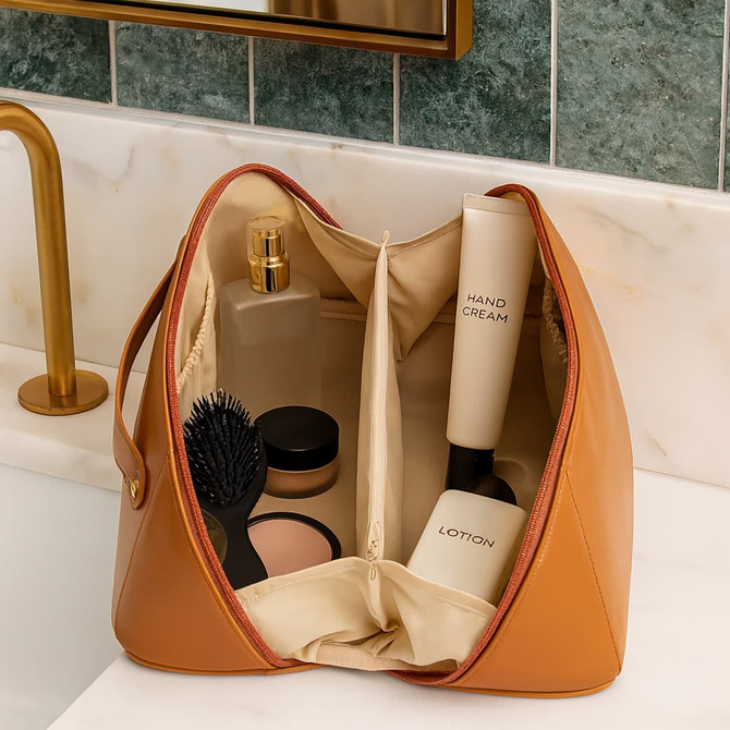 A tan toiletry bag with compartments containing a hairbrush, lotions, and cream. It has a logo inside.