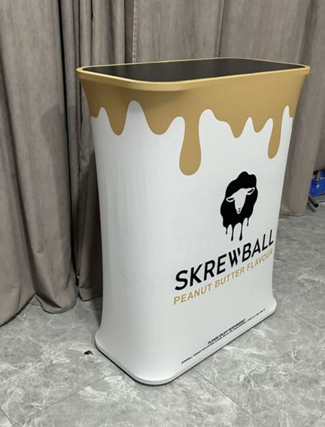 A white and gold hydraulic counter with a wavy design and a logo, set against a grey backdrop.