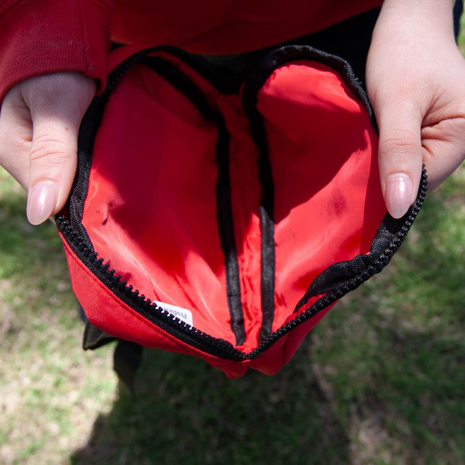 A black and red Go-Mate Belt Bag is held open, revealing its spacious interior with two compartments.
