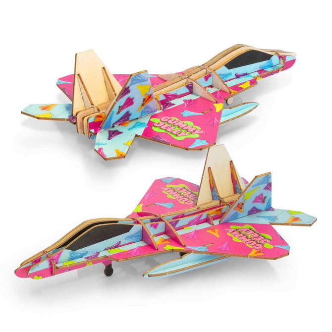 A colourful wooden model of a jet fighter in pink, blue, and various vibrant patterns, featuring a logo.