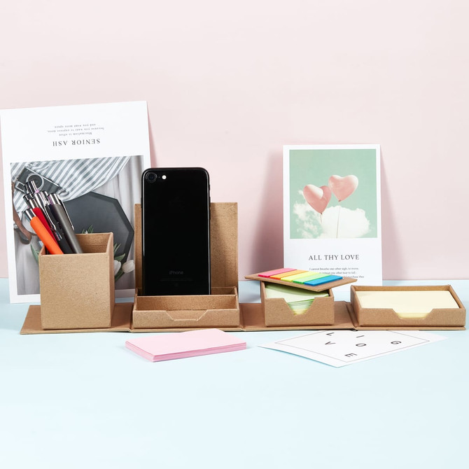 A desk organiser set in brown, featuring compartments for sticky notes, a phone, and pens against a pastel background.