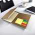 A brown memo stationery set featuring a lined notebook and colourful sticky notes, displayed on a desk with a chair and cup.