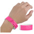 A pink Tyvek wristband is worn on a hand, with a smooth white interior. The wristband features some printed details and a logo.