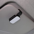 A car visor sunglass holder in black and white, mounted on a car interior visor.